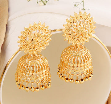 A pair of intricately designed gold-plated jhumka earrings from the Mekkna brand, featuring detailed craftsmanship and a luxurious finish.